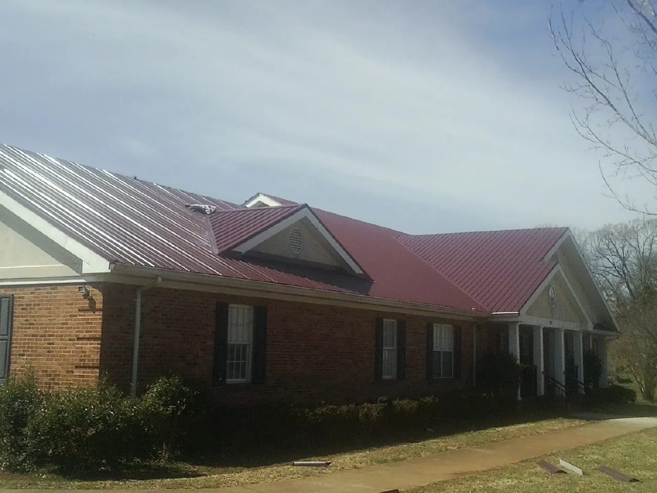 Red metal roof with gabled entries on a long brick building in New Albany