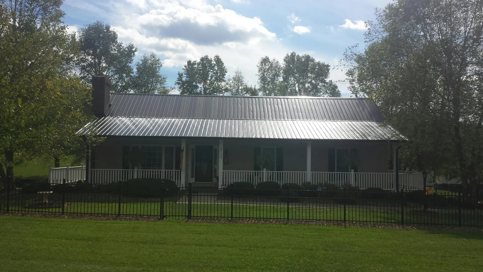 Gray metal roof on a brick ranch with a full width front porch — Gutter Guard Installation work by our crew in New Albany