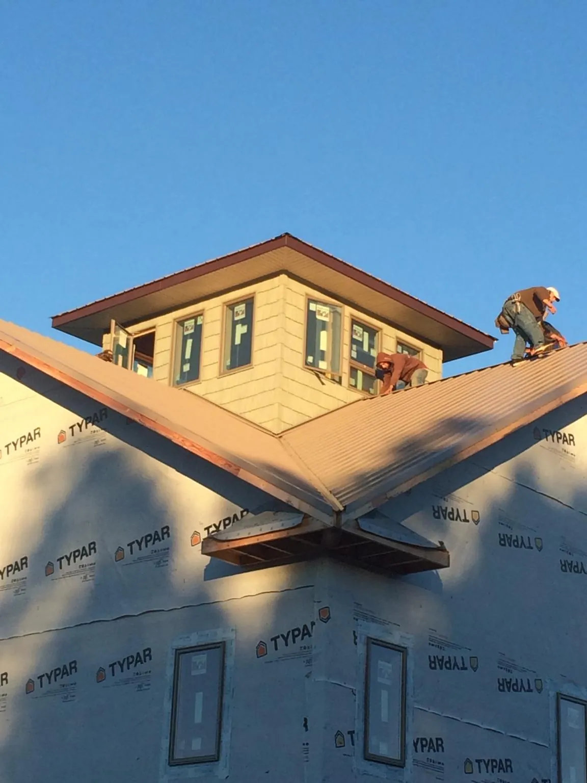 Roofers working around a rooftop cupola on a new metal roof at sunset — Roof Waterproofing in New Albany by Roofing Brothers